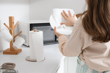 Housewife wiping dish with paper towel in kitchen, closeup
