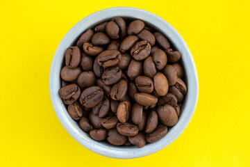 Ceramic pot with roasted coffee beans on a yellow background in Brazil
