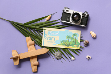 Composition with travel gift voucher, photo camera, palm leaf and wooden plane on color background