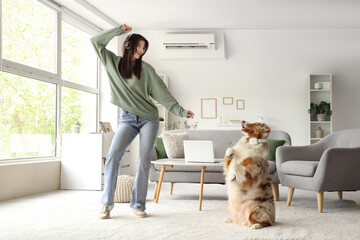 Young woman in headphones with Australian Shepherd dog dancing at home