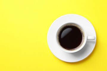 Cup of aromatic coffee on yellow background, top view. Space for text