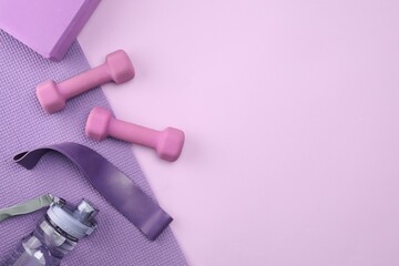 Two dumbbells, yoga block, mat, fitness elastic band and bottle on violet background, flat lay. Space for text