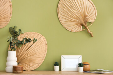 Artificial plants with photo frame and magazine on commode in room