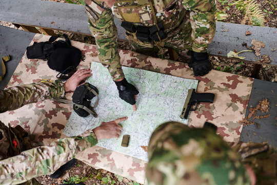 A highly trained military unit strategizes and organizes a tactical mission while studying a military map during a briefing session