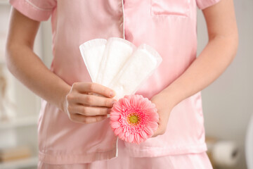 Young woman with menstrual pads and flower in restroom, closeup