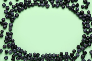 Frame made of sweet fresh blueberries on green background