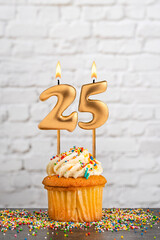 Cupcake with number 25 birthday candle - White block wall background