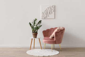 Pink armchair and coffee table with houseplant near white wall