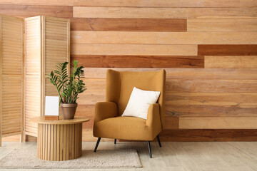 Brown armchair and coffee table with houseplant near wooden wall
