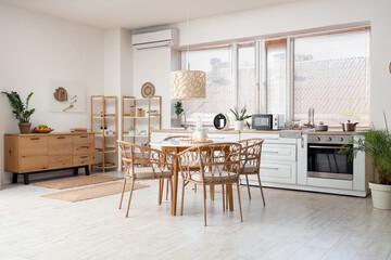 Dining table, chest of drawers, chairs and lamp in stylish kitchen