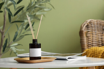 Reed diffuser and magazine on coffee table near green wall