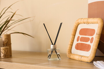 Reed diffuser, photo frame and houseplant on wooden shelf, closeup