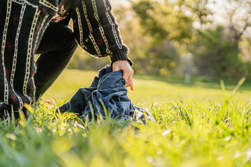 Hands Picking Up Blue Clothing in Grass Sunny Spring Time Outside Clothing Laundry