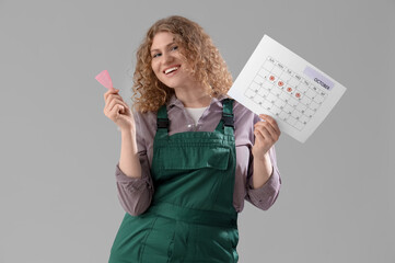 Female worker with menstrual cup and calendar on grey background