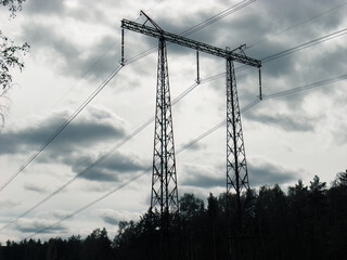 silhouette of high voltage power lines against cloudy sky