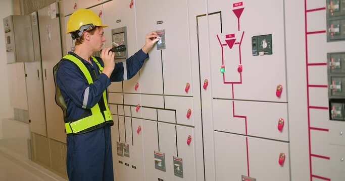 electrician electrical engineer in protective uniform checking voltage control panel screen system at electrical cabinet for generate electricity of factory in manufacture industrial	
