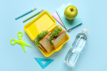 Lunchbox with tasty sandwiches, bottle of water and stationery on color background