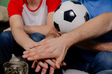 Top view, soccer fans family in front of tv putting hands together before game, closeup