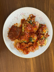 Malfatis de ricota y espinaca con tuco de salsa de tomate, estofado y salchicha.
