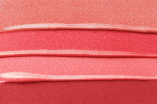 Lipstick texture background. Shiny glitter makeup swatches of different colors. Red shimmer liquid lip gloss palette smeared