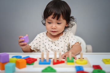 toddler baby girl playing with wooden educational geometric on table