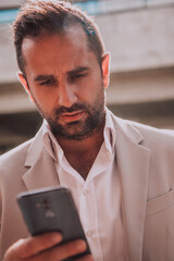 A businessman using his smartphone outdoors, showcasing the seamless integration of technology and mobility in modern professional life.