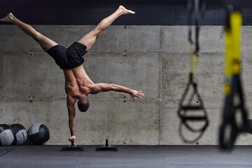 A muscular man in a handstand position, showcasing his exceptional balance and body control while...