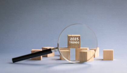 2025 Trends, text on wood block, with magnifying glass.