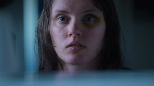 Close up of a woman coming to the mirror checking out her bruised black eye being shocked and scared. Domestic violence victim after being abused in slow motion