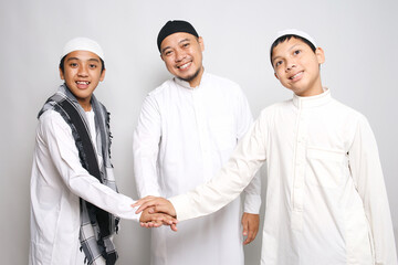 Muslim Father And Sons Stacking Hands Together With Happy Expression