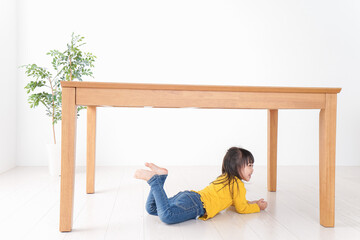 机の下に避難する子ども