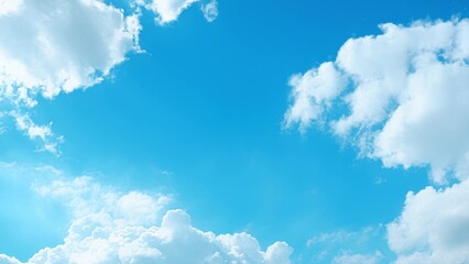 A bright blue sky adorned with fluffy white clouds. The clouds are scattered across the sky,...