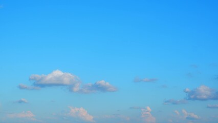 A clear blue sky with a few scattered clouds. The clouds are primarily situated in the lower part...