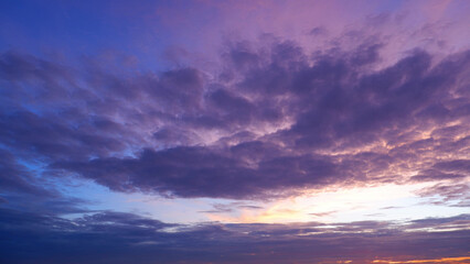 A dramatic sunset sky with a vibrant mix of deep purple and pink clouds. The lower part of the sky...