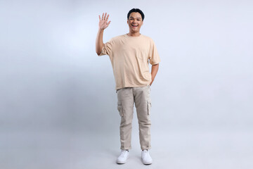 Full Length Of Friendly Young Asian Man Waving Hand Wear Casual Style Isolated On White Background