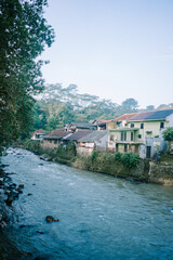 Fototapeta premium The Ciliwung River in Bogor, flowing through lush greenery and urban landscapes.