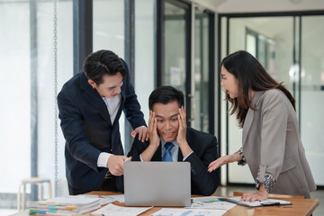 Team of stressed business professionals in office discussing problem on laptop. Overwhelmed worker receiving support and advice from colleagues.