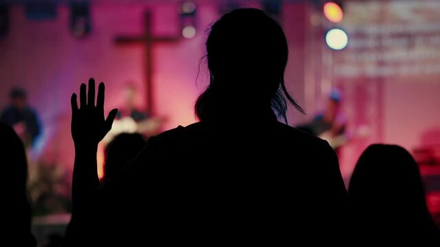 "In the church, a man is raising his hands in worship and singing praises to God. The atmosphere is filled with hope and holiness. The congregation joins in singing and praying to God. Slow motion 