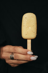 female hand is holding an ice cream eskimo at dark background