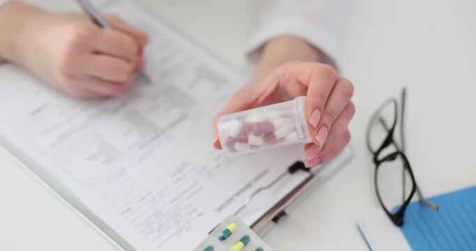 Doctor holding bottle of pills and writing prescription