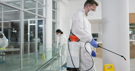 Man, biohazard suit and spray for cleaning in office, pandemic and disinfection for bacteria. Male person, lock down and caution for illness on stairs, sanitation and hazmat uniform for virus safety