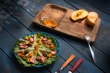 Comida. Ensalada recien preparada con una tabla de cortar con mango partido a la mitad, sobre mesa...