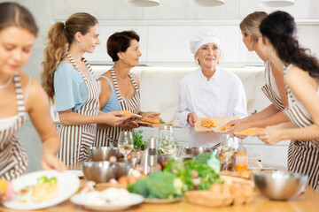 Female chef explains to women visitors of cookery courses for amateurs about delicious and simple...