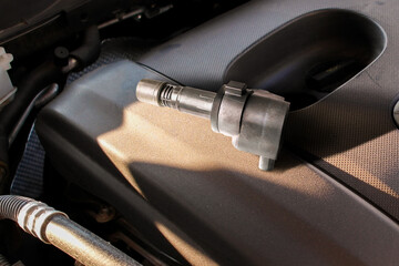 An automobile electronic ignition coil located on the engine cover for the combustion engine ignition spark plug , Car maintenance concept