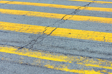 Fototapeta premium Close-up view of weathered yellow pedestrian crossing lines on an asphalt road