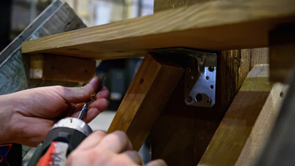 Carpenter working at workshop. Media. Worker using a screwdriver for assembling wooden construction.