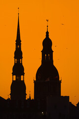 A beautiful cityscape of Riga, Latvia during sunrise. Church towers against colorful sky. City panorama in morning with buildings.