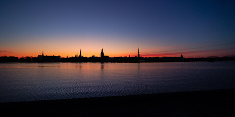 Naklejka premium A beautiful cityscape of Riga, Latvia during sunrise. Church towers against colorful sky. City panorama in morning with buildings.