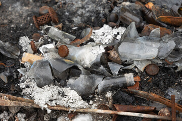 Old, rusted metal cans in burned ash. Trash in abandoned army base, burned, rusty.