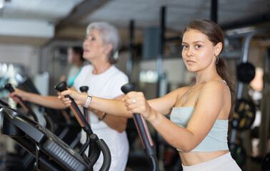 Young sporty girl working out on elliptical machine in gym. Healthy active lifestyle concept